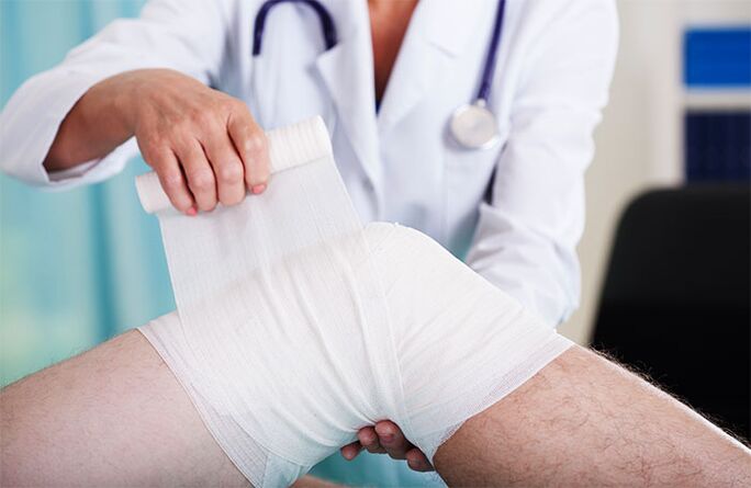 doctor bandages the knee joint with arthrosis